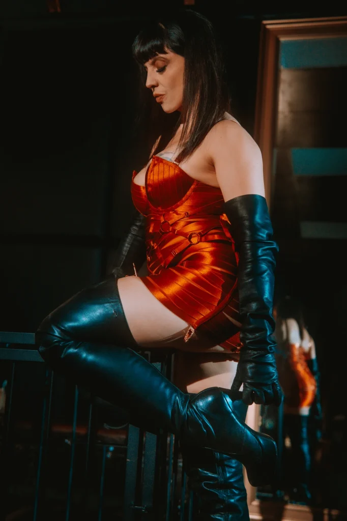 Berlin Dominatrix Lady Vyra wearing leather overknee boots and elegant red lingerie